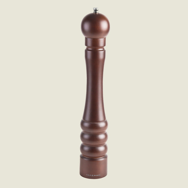 The Cole & Mason Beech Capstan Pepper Mill 400mm stands upright on a plain light background, featuring dark-stained beech wood, a rounded top, grooved base design, and adjustable grind for customized seasoning.