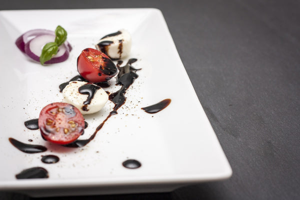 tomatoes and mozzarella on a plate with balsamic vinegar