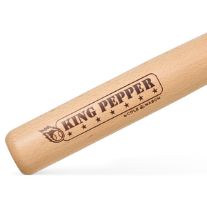 A close-up of the 710mm King Pepper Baseball Bat Pepper Mill by Cole & Mason, featuring engraved branding and star designs, reminiscent of a baseball bat.