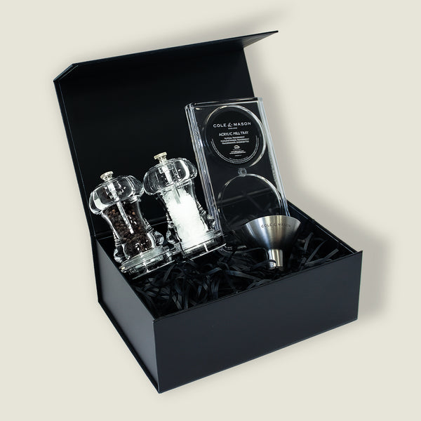 The Acrylic Capstan Mill Christmas Gift Hamper by Cole & Mason features salt and pepper mills, a stainless steel funnel, and an acrylic fill tray in a black gift box with shredded paper—an ideal seasoning present.