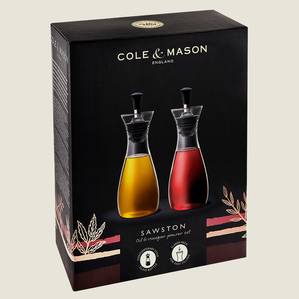 Set of two Cole & Mason UK Haverhill Oil & Vinegar Pourers (450ml) with adjustable rubber stoppers, glass bottles, and black pour spouts—oil in yellow, vinegar in red—displayed on a black background with gold accents.