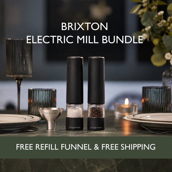Elevate your table setting with the Cole & Mason Brixton Electric Mill Matt Black Set—two rechargeable electric salt and pepper mills that sit stylishly among plates, glasses, flowers, a glowing candle, and the included handy refill funnel. Equipped with a precision ceramic grinding system and convenient USB-C charging, this elegant set comes with a free refill funnel and free shipping.