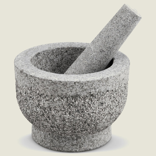The Cole & Mason Langley Pestle & Mortar, made from natural granite in gray, features the pestle resting inside the mortar and is displayed on a light neutral background—perfect for preparing spice rubs.