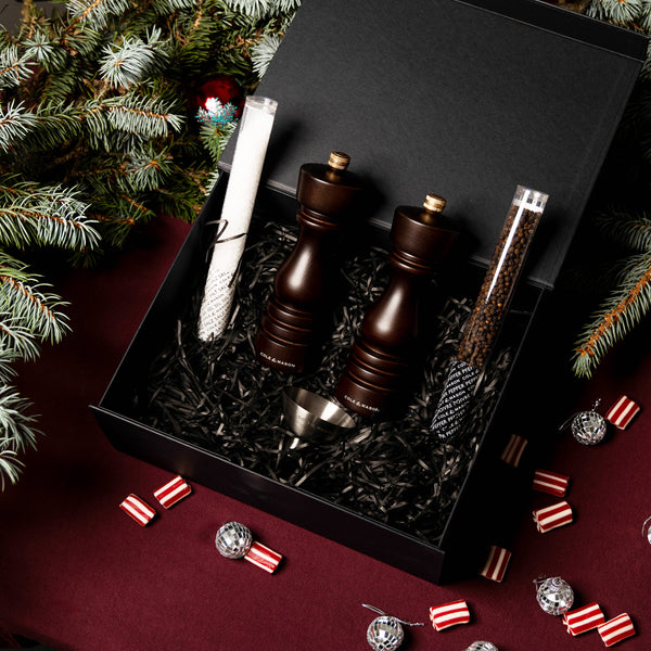 The Cole & Mason London Chocolate Wood Mill Christmas Gift Hamper features two wooden grinders on a burgundy tablecloth with festive decor—ideal for Christmas gift hampers.