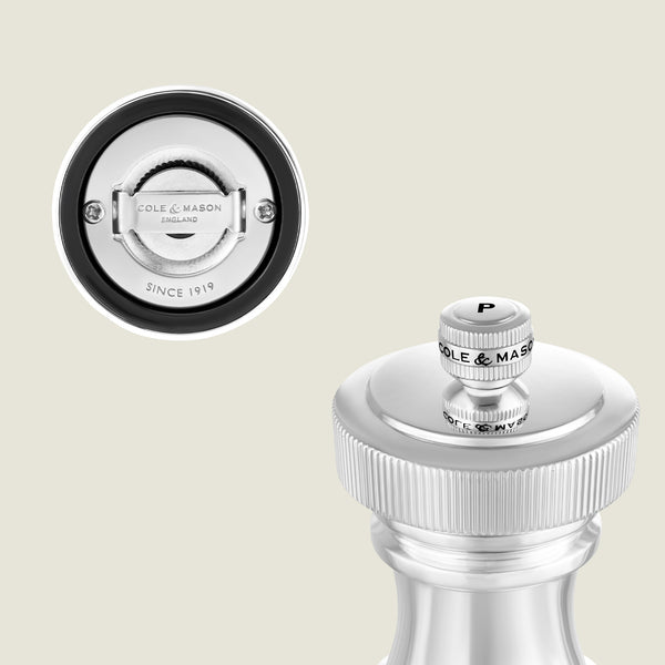 Close-up image of a silver Cole & Mason pepper grinder. The top view shows the brand name and a P for pepper, while the bottom reveals the adjustable grinding mechanism and brand details.