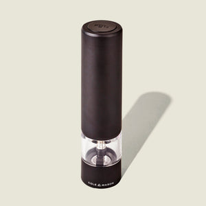 The Cole & Mason Brixton Electric Mill Matt Black GS is a black electric salt or pepper grinder featuring a clear middle section that reveals the ceramic grinding mechanism inside. Designed for convenient one-handed operation, it has the Cole & Mason brand printed at the base.