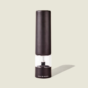 The Cole & Mason Brixton Electric Mill Matt Black GS is an electric pepper grinder with a ceramic grinding mechanism and a clear middle section for easy viewing, designed for convenient one-hand operation. The mill, branded with the Cole & Mason logo on its base, stands upright against a light beige background.