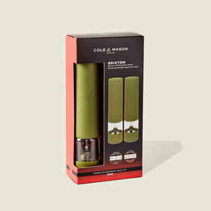 The Cole & Mason Brixton Electric Mill Olive Green GS set includes two mills with clear bases and olive green tops, each designed for easy one-handed operation and equipped with a durable ceramic grinder for consistent seasoning. The packaging features black, red, and green accents along with product details on the front.
