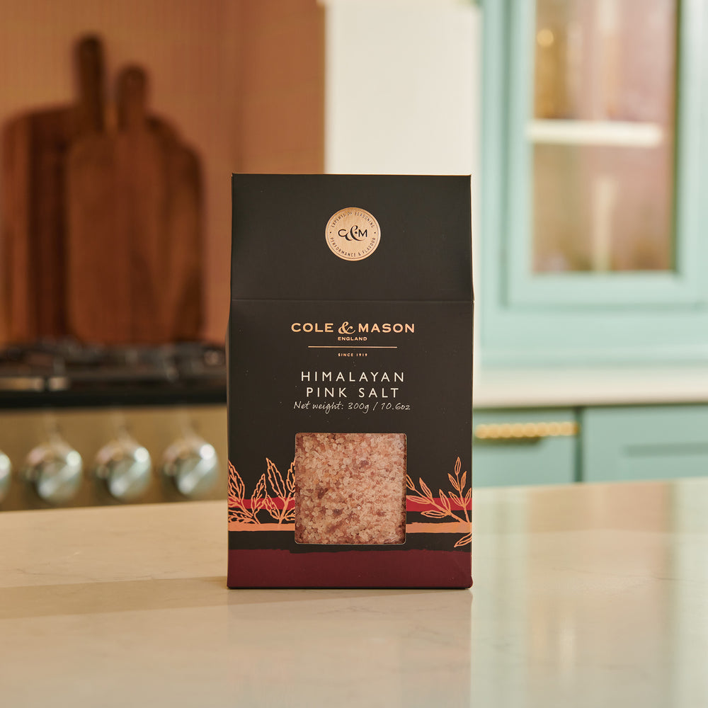 The Cole & Mason Pink Himalayan Salt Box features a clear window showing vibrant salt crystals. Its brown and black box with white text is ideal for refilling salt mills and provides nutritional info on the side.