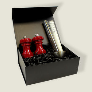 The Cole & Mason Hoxton Red Gloss Mill Christmas Gift Hamper includes two red mills, three spice tubes, and a metal funnel in black shredded paper—ideal for Christmas hamper boxes.