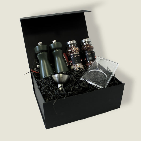 The Cole & Mason Kenton Mills in Rosemary Christmas Gift Hamper features two dark green grinders, two jars of aromatic salt & pepper refill, a small funnel, and a glass in a sleek black gift box—perfect for Christmas gifting.