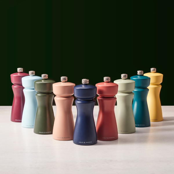 Ten Cole & Mason Kenton Salt & Pepper Mills in Persian Blue Salt are arranged in rows on a light surface against a dark background. Each mill showcases a modern, sleek design with a silver knob on top and features a high-quality ceramic grinding mechanism for durability. These grinders also include adjustable grind settings, letting you customize your seasoning exactly to your preference.