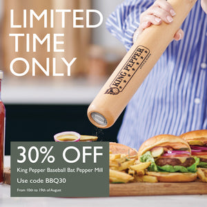 A person uses the Cole & Mason King Pepper Baseball Bat Pepper Mill 710mm—with an adjustable grind and a durable carbon steel grinder—over burgers and fries. Get 30% off with code BBQ30 from August 10th to 19th.