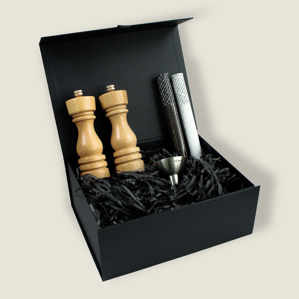 The London Natural Beech Mill Christmas Gift Hamper by Cole & Mason features two wooden grinders, a small metal funnel, and two sealed tubes in black shredded paper inside a stylish gift box—ideal for Christmas hampers.