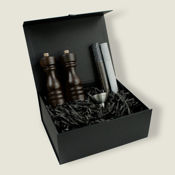The Cole & Mason London Chocolate Wood Mill Christmas Gift Hamper features two wooden mills, pepper tube, metal funnel, and black shredded paper in a black gift box—an elegant choice for Christmas gift hampers.