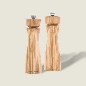 #salt&pepperset Two Portobello Olive Wood Salt & Pepper Mills by Cole & Mason, each with a precision grinding mechanism and natural grain pattern, stand side by side on a light background. Both are branded “Cole & Mason” at the base.