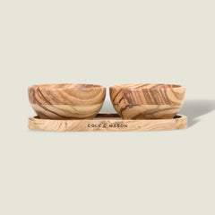 The Cole & Mason Portobello Olive Wood Pinch Pot Set features two small pots with unique grain patterns on a matching tray engraved with the brand name. The set is displayed against a plain, light beige background.