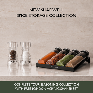 Two salt and pepper shakers beside a rack of four airtight glass spice jars filled with colorful spices, featuring the Shadwell Drawer-Fit Spice Storage collection and a free shaker set.
