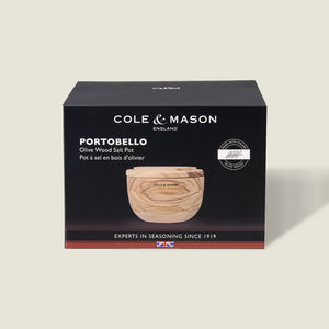 A Cole & Mason box displays the Portobello Olive Wood Salt Cellar—a small, round wooden container with a lid. The mostly black packaging features white text and a product image, making it perfect for stylish kitchen decor.