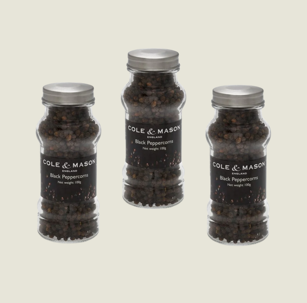 Three clear glass jars with silver lids, labeled in black and white, contain Cole & Mason UK Black Peppercorns in Refill Jars 100g x3. Displayed on a plain background, theyre perfect for refilling your Cole & Mason mills.