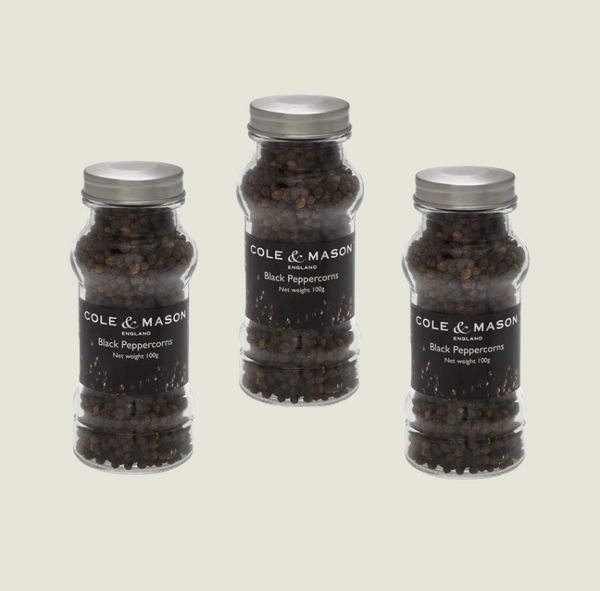Three clear glass jars with silver lids, labeled in black and white, contain Cole & Mason UK Black Peppercorns in Refill Jars 100g x3. Displayed on a plain background, theyre perfect for refilling your Cole & Mason mills.