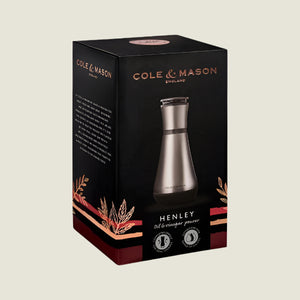 The Cole & Mason UK Henley Oil & Vinegar Pourer 180mm comes in black and brown packaging with a carafe design image of the stainless steel product and decorative leaf illustrations.