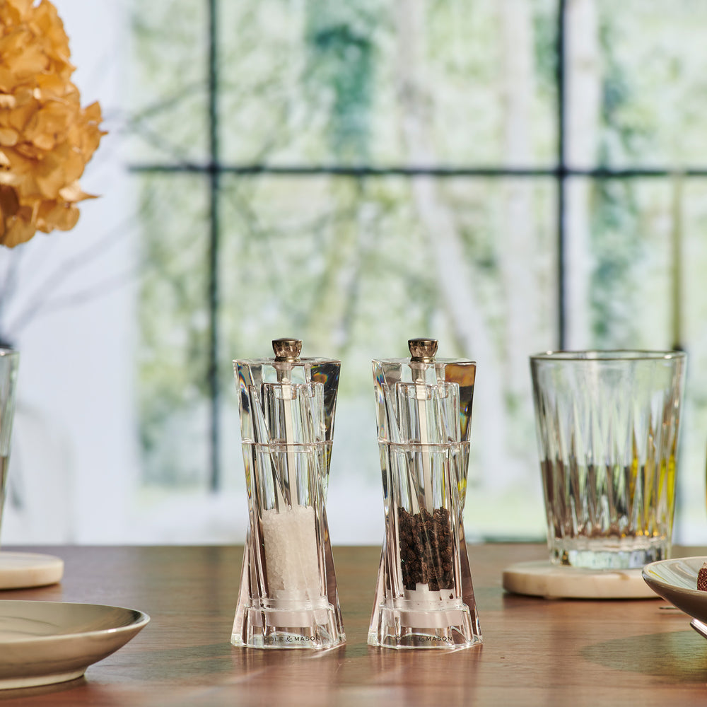 The Cole & Mason Aldeburgh Salt & Pepper Mill Set features two clear acrylic mills with silver tops, a modern faceted design, and premium adjustable grinders for fresh peppercorns or salt crystals.