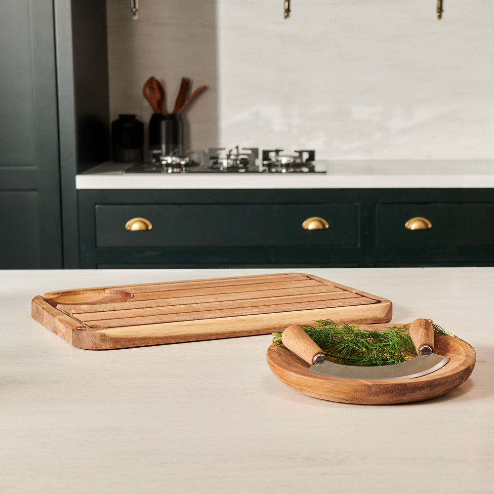 The Cole & Mason Berden Carving Board & Ashden Mezzaluna Bundle features a grooved acacia wood board with a bowl and dual-handled mezzaluna—perfect as an elegant herb chopping set.