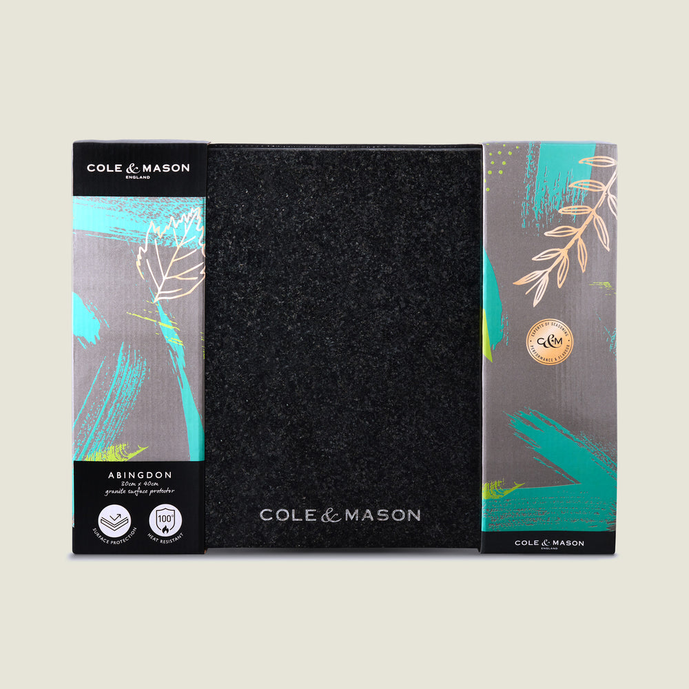 The Cole & Mason Black Granite Surface Protector features a square, textured black granite design with the brand name printed in white—an elegant and heat-resistant addition to your kitchen décor.