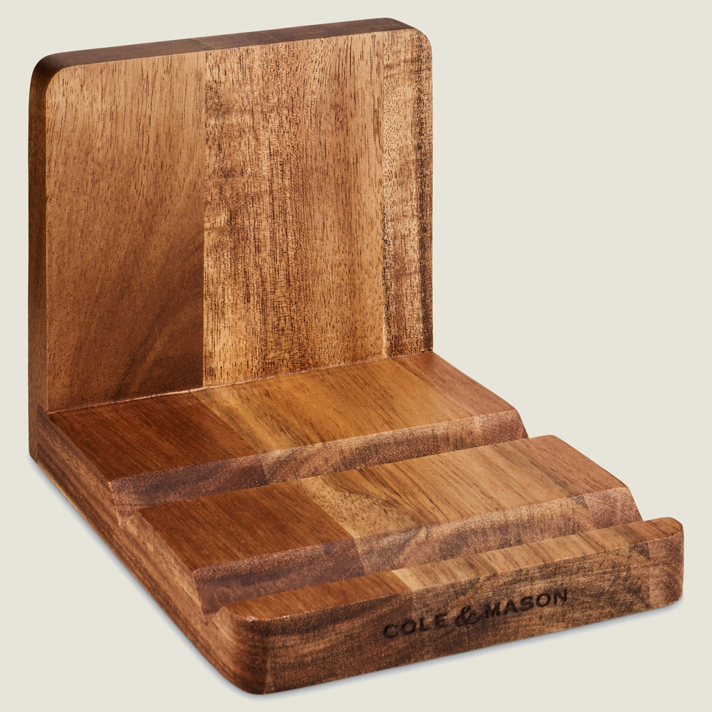 The Buckland Acacia Recipe Cook Book & Tablet Stand by Cole & Mason UK features three angled slots, ideal for holding devices, cookbooks, or recipe cards. Cole & Mason is branded on the front edge.