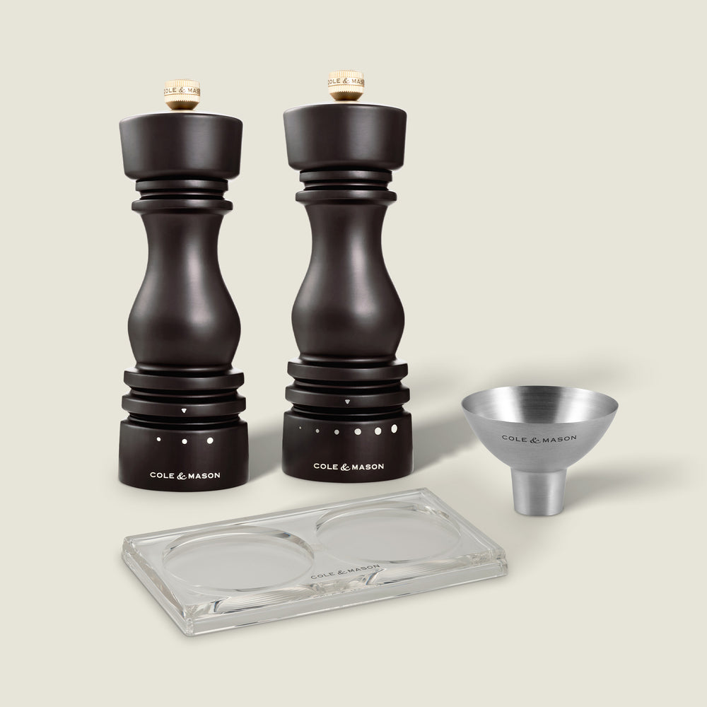 The Mix & Match #3 set by Fast Bundle features two dark wood salt and pepper mills with labels, a small metal funnel, and a clear rectangular tray with circular indentations on a light background.