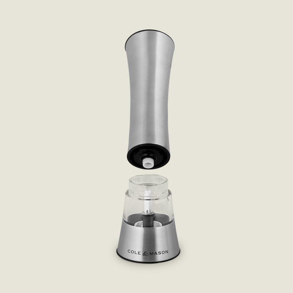 The Cole & Mason Burford Electronic Single Mill is a stainless steel pepper grinder with one-handed operation, adjustable grind settings, and a visible electronic mechanism when the top is lifted. The clear chamber is labeled “Cole & Mason.”.