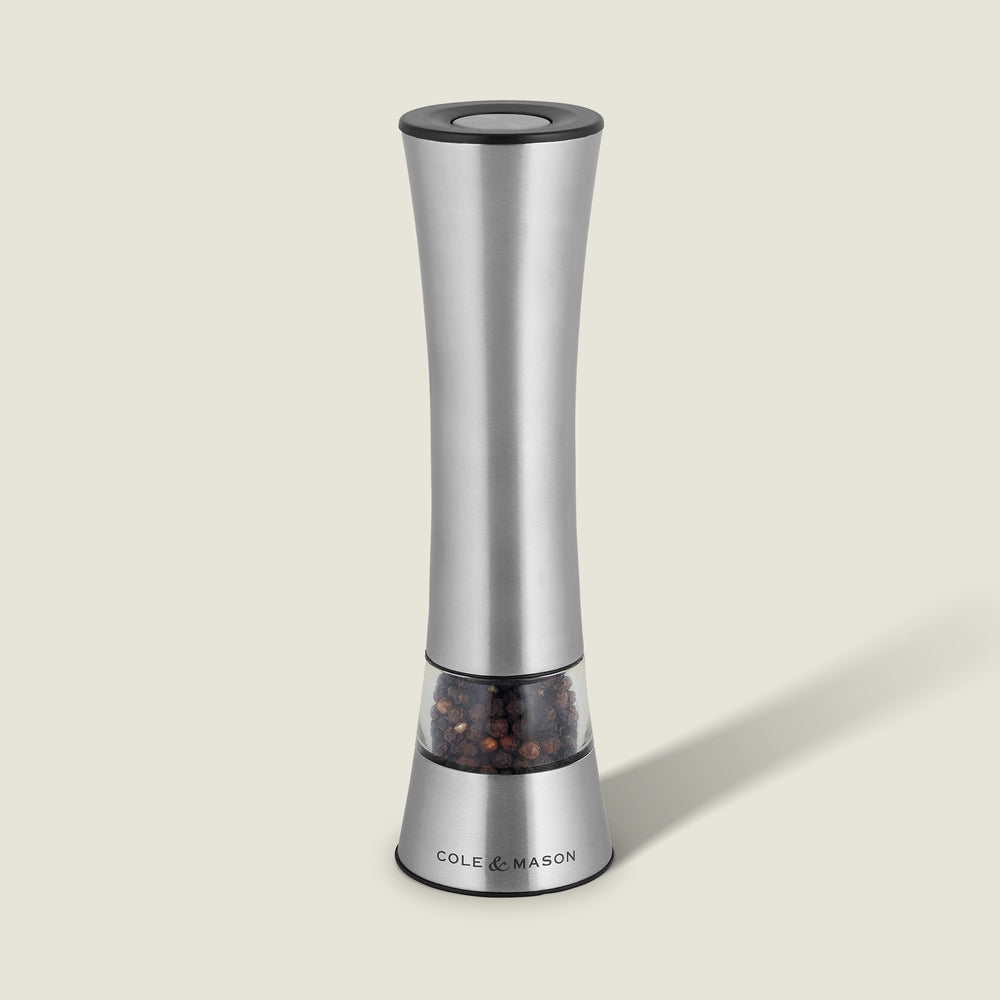 The Cole & Mason Burford Electronic Single Mill is a sleek stainless steel pepper grinder with adjustable grind settings, a transparent peppercorn chamber, and a labeled base. It casts a soft shadow against a light background.