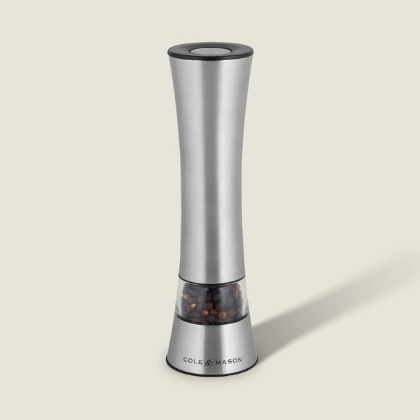 The Cole & Mason Burford Electronic Single Mill is a sleek stainless steel pepper grinder with adjustable grind settings, a transparent peppercorn chamber, and a labeled base. It casts a soft shadow against a light background.