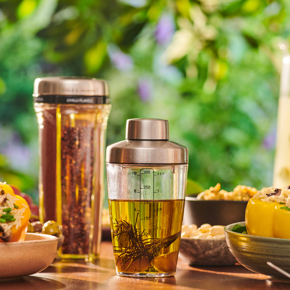 The Cole & Mason Cambourne Salad Dressing Shaker features clear glass with a stainless steel lid and measurement lines in ounces, milliliters, and cups—ideal for mixing cocktails, vinaigrettes, or dressings on any surface.