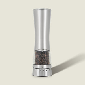 A sleek, silver Cole & Mason Electric Derwent Pepper Mill with a transparent lower section displaying black peppercorns stands upright on a light background.