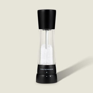 #salt The Cole & Mason Derwent Matt Black Salt & Pepper Mill stands upright on a light background, featuring an acrylic body with a transparent middle, adjustable grind settings, and sleek black top and base.