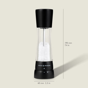 #salt&pepperset A Cole & Mason Derwent Matt Black Salt & Pepper Mill with an acrylic body and adjustable grind settings, measuring 190 mm tall by 60 mm wide, is shown on a light beige background. The mill features black and clear accents.