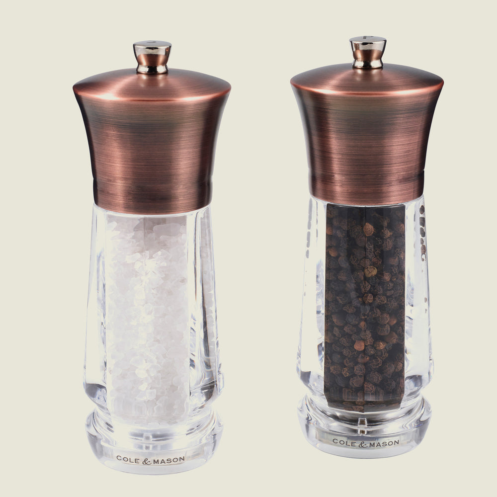 The Cole & Mason UK Exford Salt & Pepper Mill 160mm set features clear glass mills with copper tops and Precision+ grinders, pre-filled for convenience—an elegant gift choice for any kitchen.