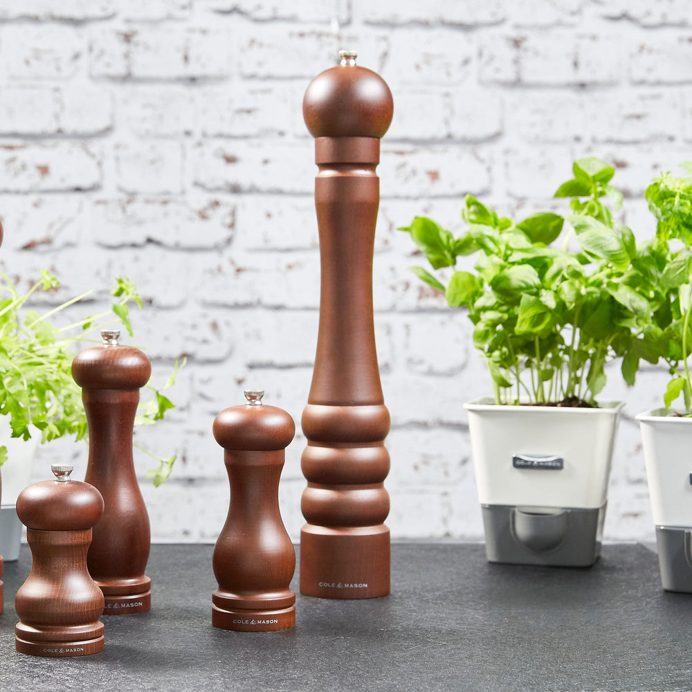 The Cole & Mason Beech Capstan Pepper Mill 400mm stands upright on a plain light background, featuring dark-stained beech wood, a rounded top, grooved base design, and adjustable grind for customized seasoning.