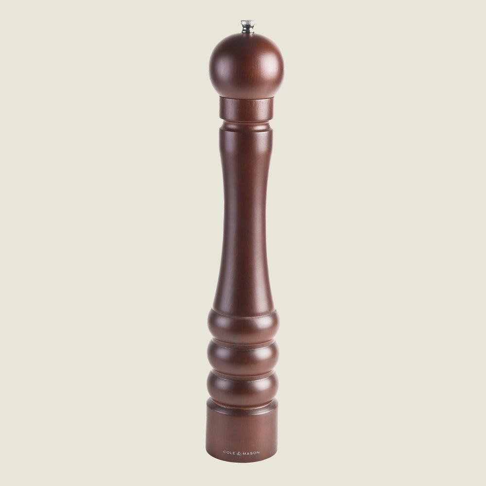The Cole & Mason Beech Capstan Pepper Mill 400mm stands upright on a plain light background, featuring dark-stained beech wood, a rounded top, grooved base design, and adjustable grind for customized seasoning.