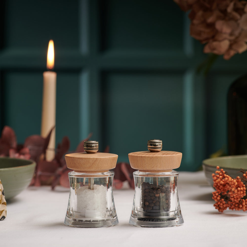 The Cole & Mason Holborn Mill Christmas Gift Hamper includes two clear glass spice jars with wooden lids, a metal funnel, and an acrylic fill tray in a black box—perfect for gifting or pairing with your Holborn Salt and Pepper Mills.