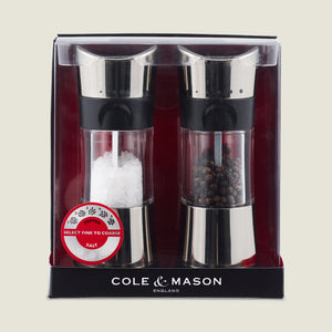 The Cole & Mason Horsham Salt & Pepper Mills boxed set features stainless steel tops, high-performance adjustable grinders, and comes pre-filled with coarse salt and peppercorns in clear packaging with a red and black background.