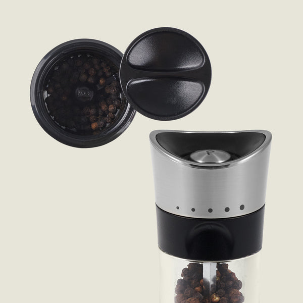 The Cole & Mason Horsham Salt & Pepper Mills feature stainless steel and glass construction, a black plastic top, an open lid showing whole peppercorns, and adjustable settings for customized grinding.