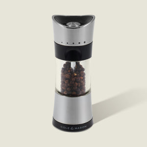A Cole & Mason Horsham Salt & Pepper Mill, crafted from stainless steel and glass, stands upright on a light background. This high-performance grinder features adjustable settings for fresh peppercorns. Part of the Salt & Pepper Mills collection.