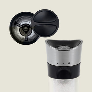 A close-up of Cole & Mason’s Horsham Salt & Pepper Mills shows a stainless steel top, black accents, and visible salt crystals, with the open lid from above revealing its high-performance grinding mechanism.