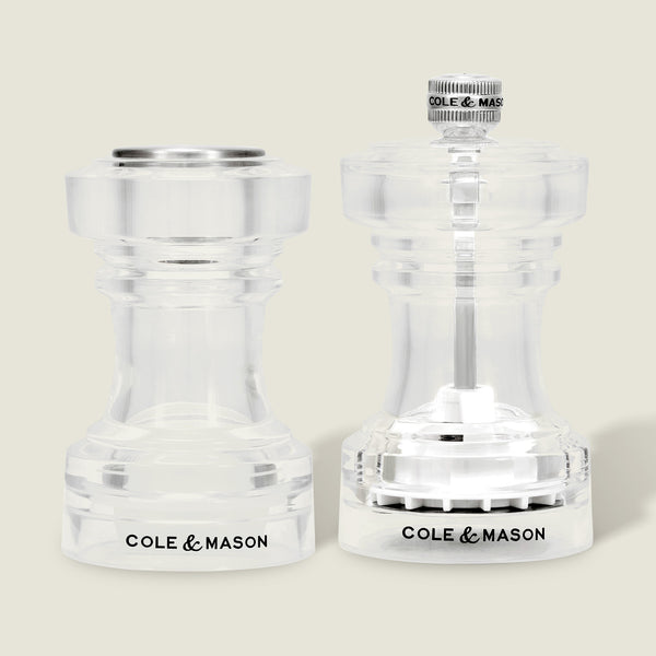 A pair of Cole & Mason Acrylic Salt Shaker & Pepper Mill Set (104 mm) are displayed side by side on a light background. Both mills feature clear acrylic bodies with the Cole & Mason logo at the base, flat and round tops, and visible grinding mechanisms that allow you to adjust the coarseness of your spices for a customizable seasoning experience.