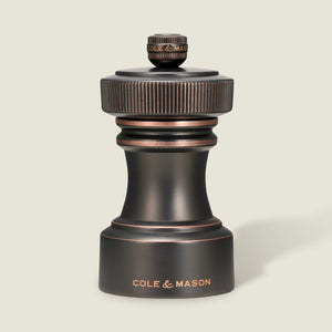 Set against a light background, the Hoxton Salt and Pepper Mill Set in antique bronze from Cole & Mason showcases refined craftsmanship, with “COLE & MASON” engraved on the base. Elegantly presented in a gift box, this striking set is a sophisticated addition to any table.