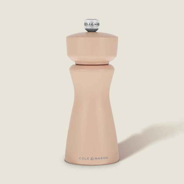 A Cole & Mason Kenton Salt & Pepper Mill in Himalayan Salt, featuring a modern, curved design with a metal knob on top and a durable ceramic grinding mechanism, is set against a plain, light background.