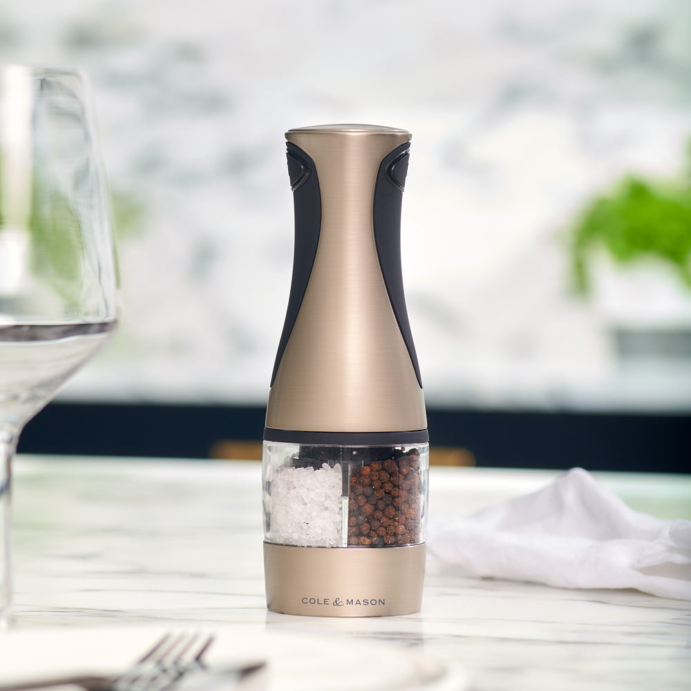 The Cole & Mason Kew Electronic 2-in-1 Duo Mill, a stainless steel and black electric grinder with a clear center for salt and pepper, features adjustable grind settings and stands upright against a light background.